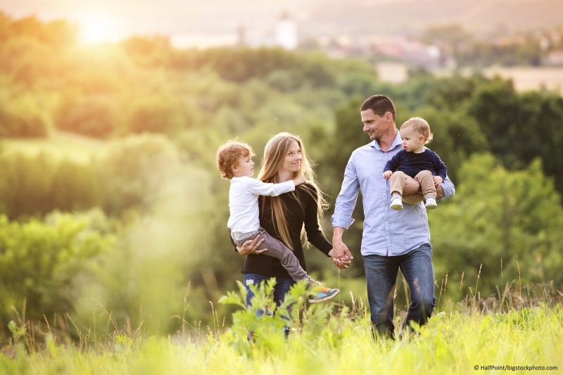 Happy young family spending time together outside in green nature.